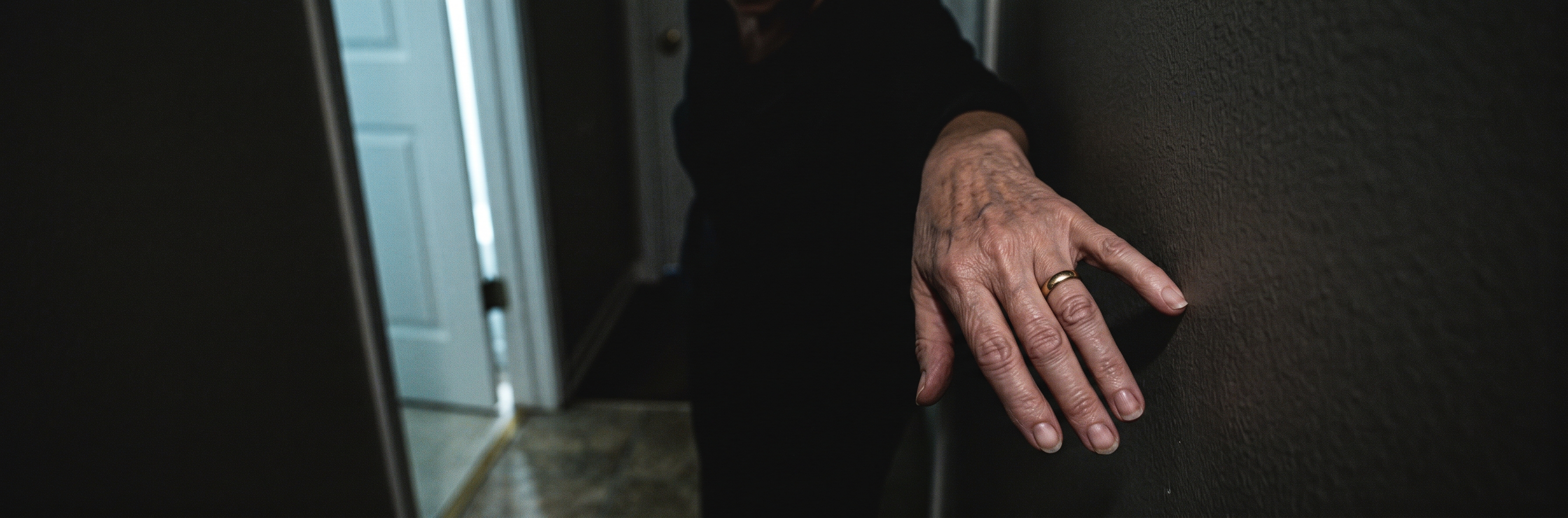 A hand braced against a hallway wall in the dark, on the way to the bathroom